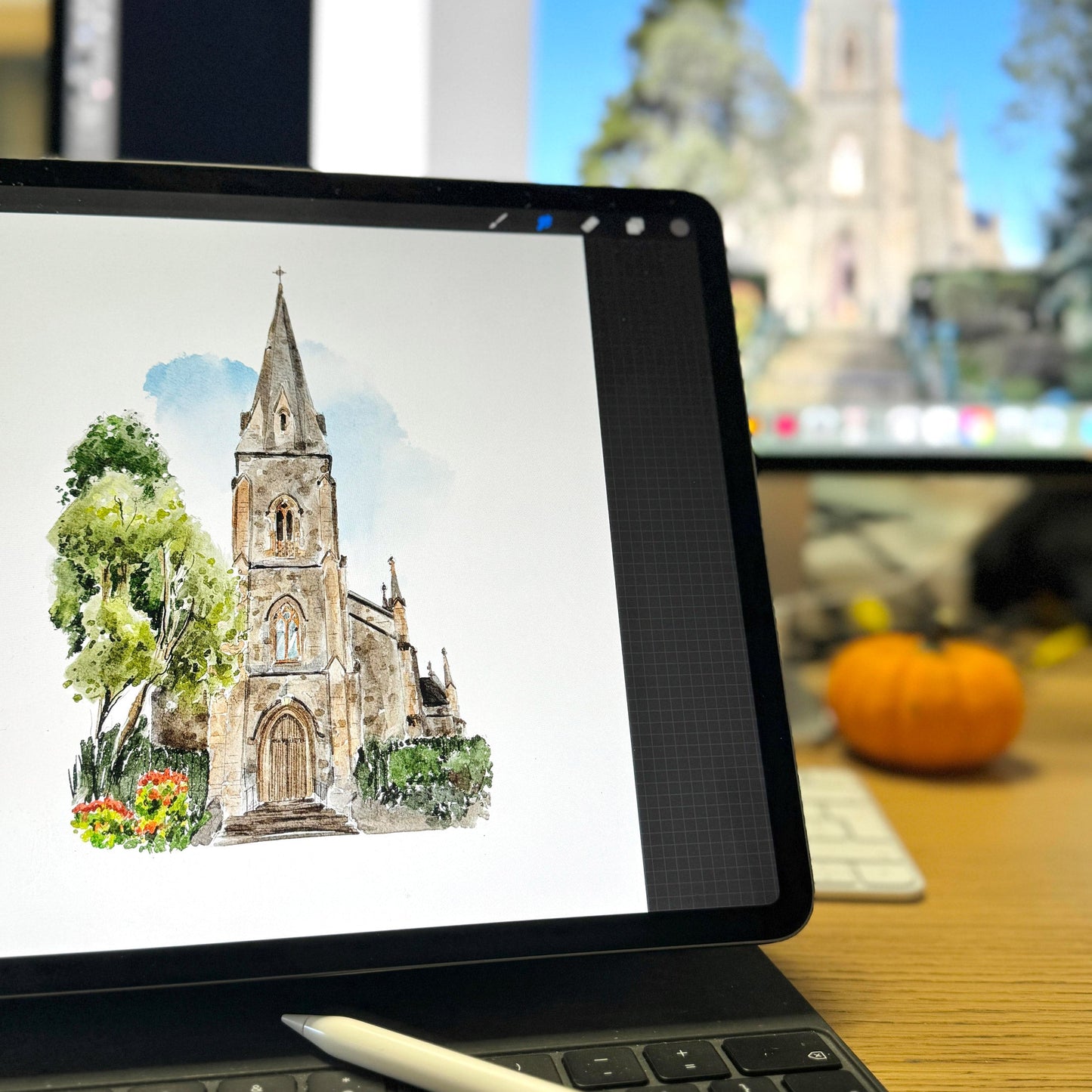Ipad with a digital drawing of a church on the screen, with a blurred outdoor scene in the background.
